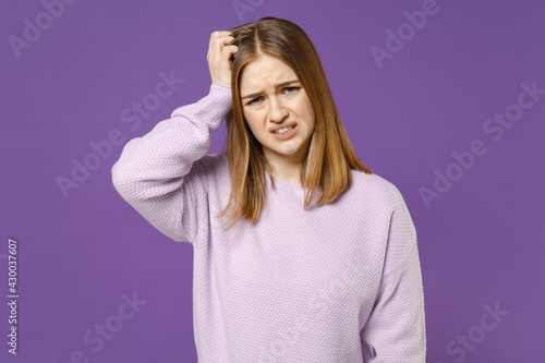 Young sad troubled puzzled thoughtful disappointed confused student woman 20s in purple knitted sweater scratch hold head isolated on violet color background studio portrait People lifestyle concept © ViDi Studio