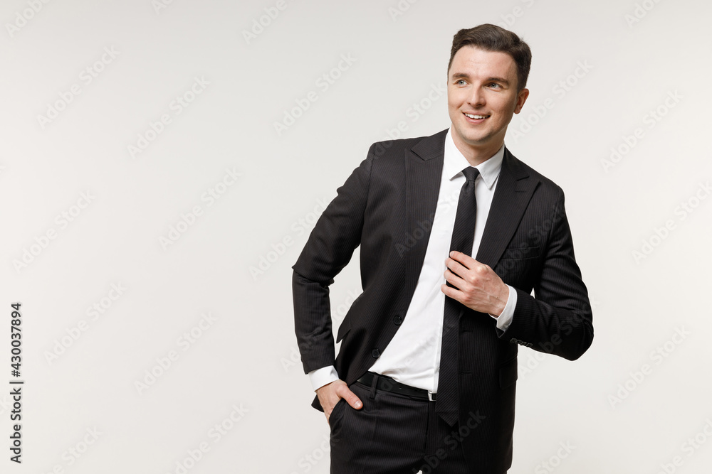 Young confident employee business corporate lawyer man 20s in classic formal black grey suit shirt tie work in office keeping hands in pockets look aside isolated on white background studio portrait Young confident employee business corporate lawyer man 20s in classic formal black grey suit shirt tie work in office keeping hands in pockets look aside isolated on white background studio portrait