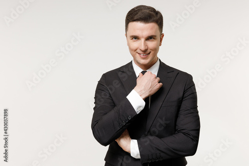 Young confident shrewd successful employee business corporate lawyer man in classic formal black grey suit shirt tie work in office corrects tuxedo tie isolated on white background studio portrait