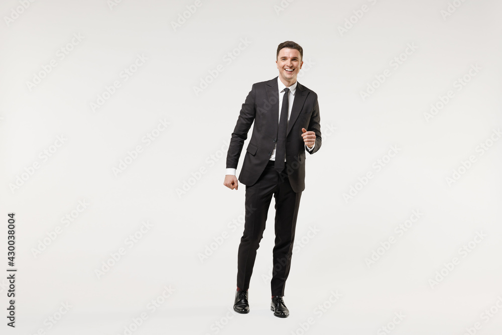 Full length young happy smiling successful employee business corporate lawyer man 20s wear classic formal black grey suit shirt tie work in office walk go isolated on white background studio portrait. Full length young happy smiling successful employee business corporate lawyer man 20s wear classic formal black grey suit shirt tie work in office walk go isolated on white background studio portrait.