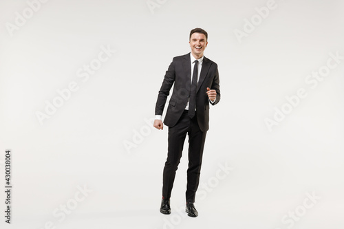 Full length young happy smiling successful employee business corporate lawyer man 20s wear classic formal black grey suit shirt tie work in office walk go isolated on white background studio portrait.