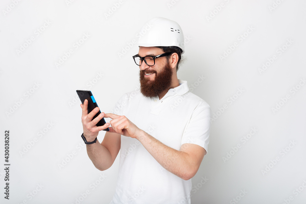 Young man wearing a protection hard hat is looking at his tablet. Young man wearing a protection hard hat is looking at his tablet.
