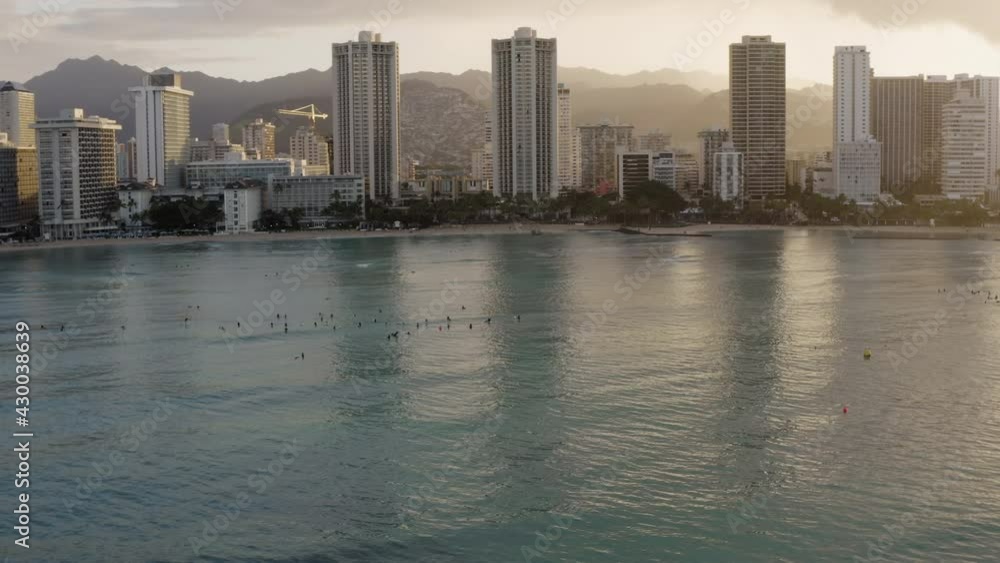 Aerial panorama of tall buildings on Waikiki Beach coast and surfers waiting for waives at sunrise, Hawaii Aerial panorama of tall buildings on Waikiki Beach coast and surfers waiting for waives at sunrise, Hawaii