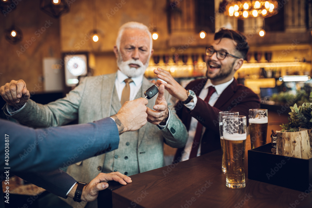 Three business people celebrating successfully done job at restaurant. One man taking car key from his drunk business partner. Three business people celebrating successfully done job at restaurant. One man taking car key from his drunk business partner.