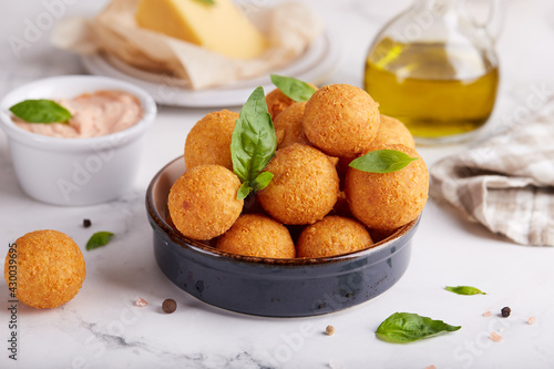 Deep fried Cheese balls. Delicious homemade appetizer. Freshly baked croquettes, served with basil leafs and sauce.