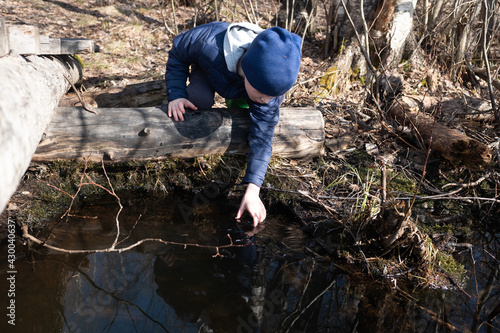 the boy bent down on the pond to wash his hands. concept of outdoor recreation in the forest, travel. spring came.