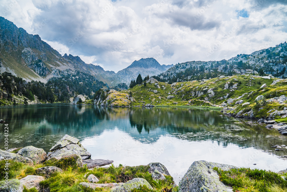Landscape of mountain lake surrounded by mountains reflected in the water. Concept of mountain trip, summer vacations and nature. Circo Saboredo, Aran Valley-Pyrenees, Catalonia, Spain.