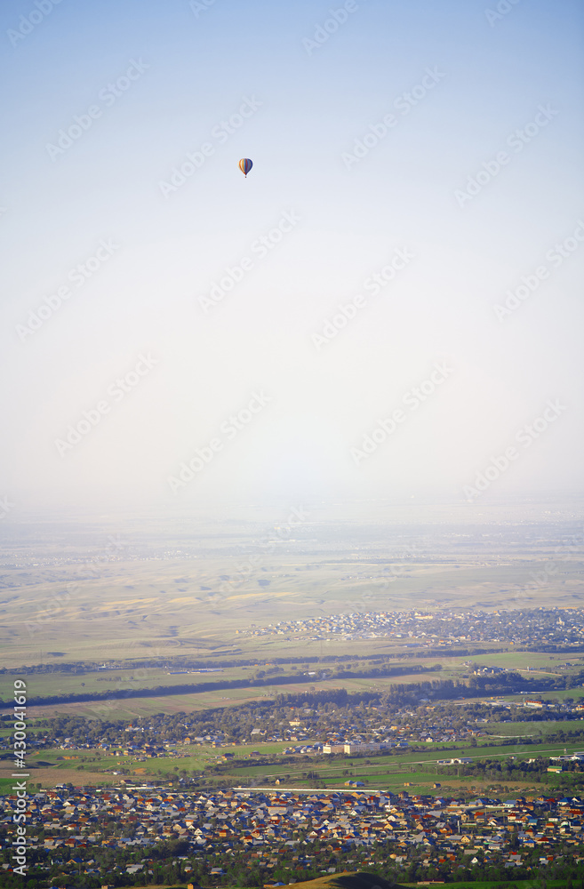 Hot air balloon above the green field and villages Hot air balloon above the green field and villages