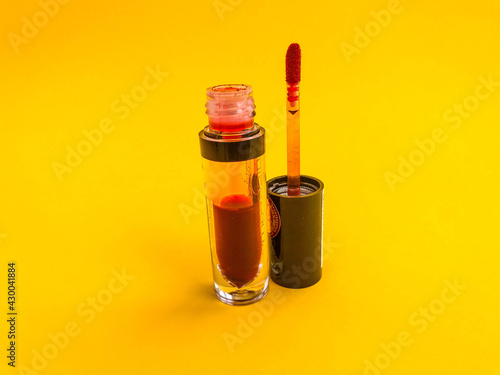 Beautiful fashionable beauty cosmetic glamorous red liquid matte lipstick in a jar for applying makeup on the lips on a yellow gentle background