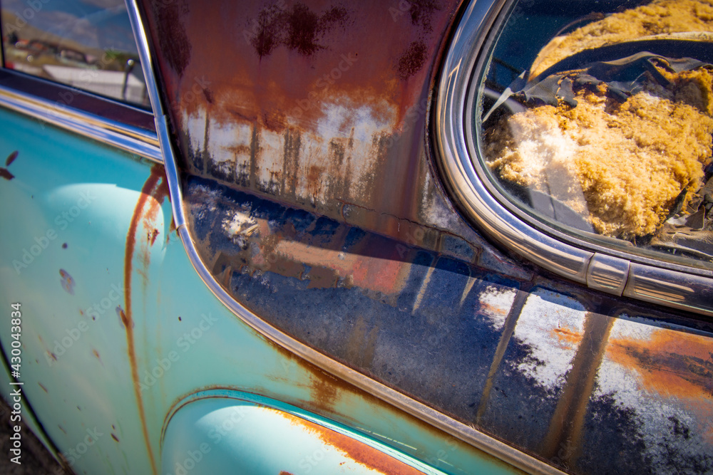 Exterior detail of a junked vintage retro vehicle in a junkyard.