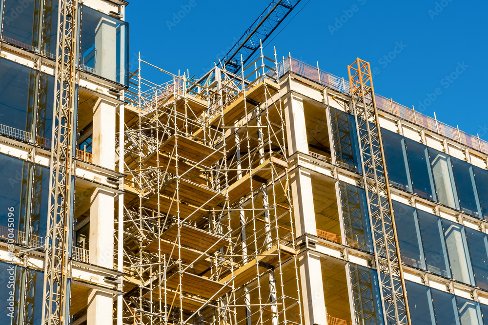 Modern tall building construction site. Metal frame and a lot of glass. Blue cloudy sky. Building new residential and office space concept.