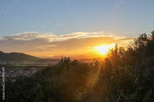 Sunset over a mountain with beautiful vegetation with blue summer sky.