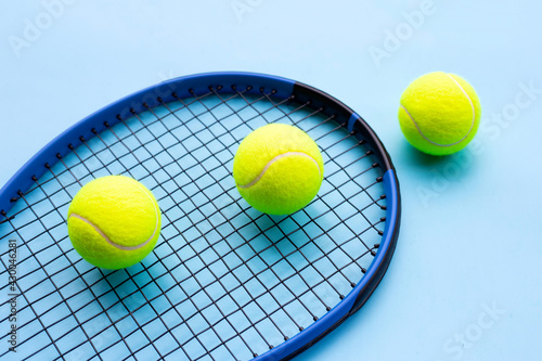 Tennis racket with balls on blue