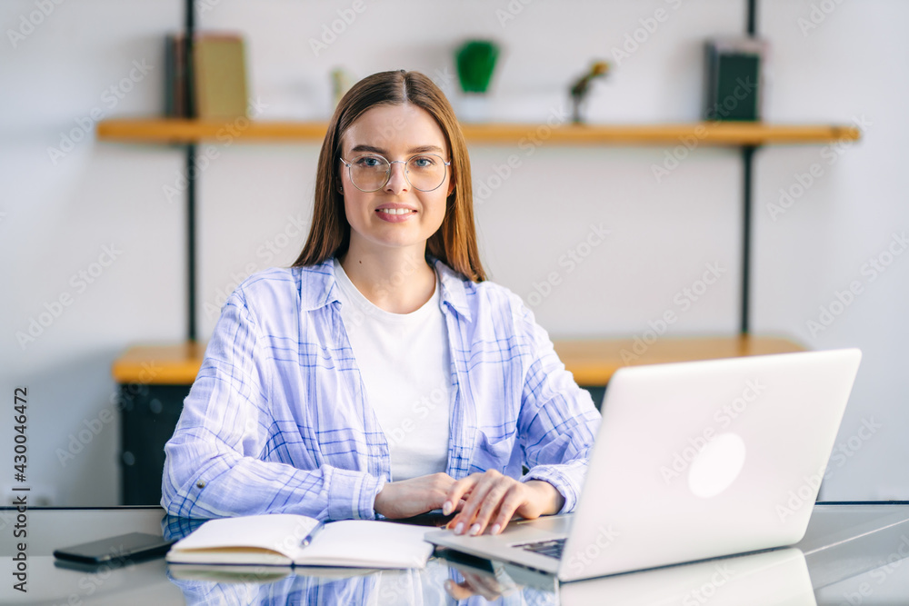 Young woman sitting at table at home working using laptop computer with happy face with confident smile. Young woman sitting at table at home working using laptop computer with happy face with confident smile.
