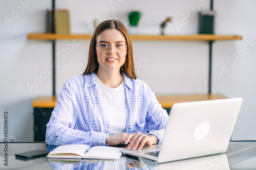 Young woman sitting at table at home working using laptop computer with happy face with confident smile.