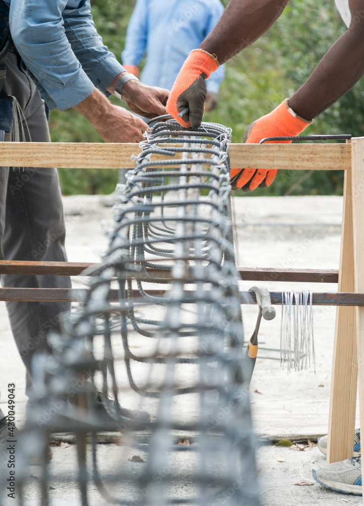 dramatic image of men working together on job site tying rebar columns