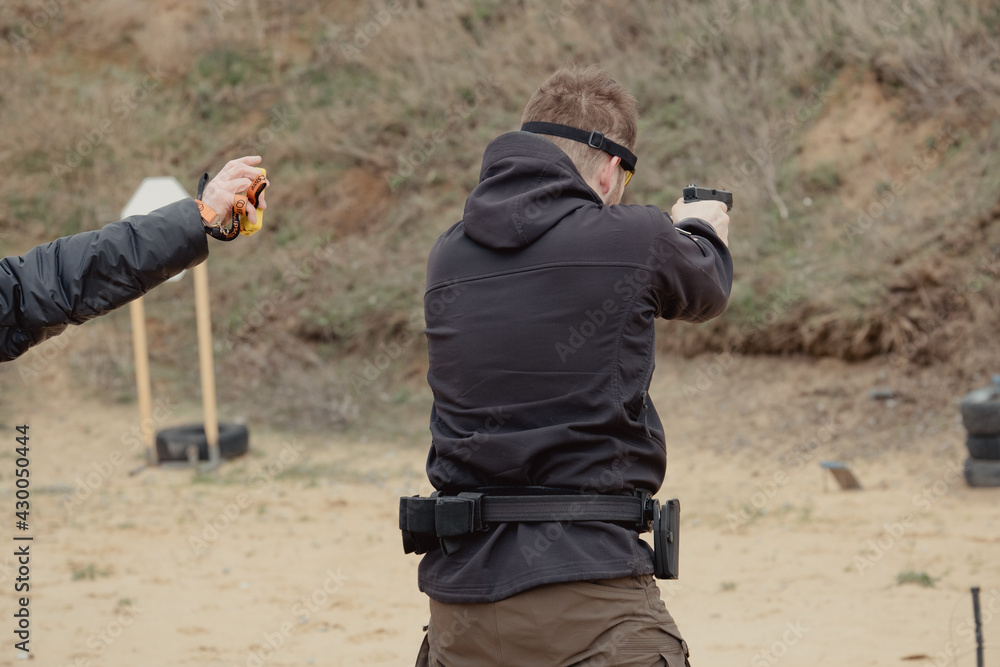 Man fires automatic handgun pistol during training in practical shooting. Man with gun, gangster. Blur crazy young man aiming automatic gun at target. 25 April 2021, Ryazan, Russia