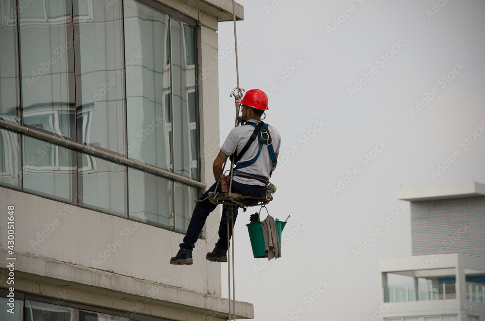 tall building glass cleaner worker with helmet and bucket