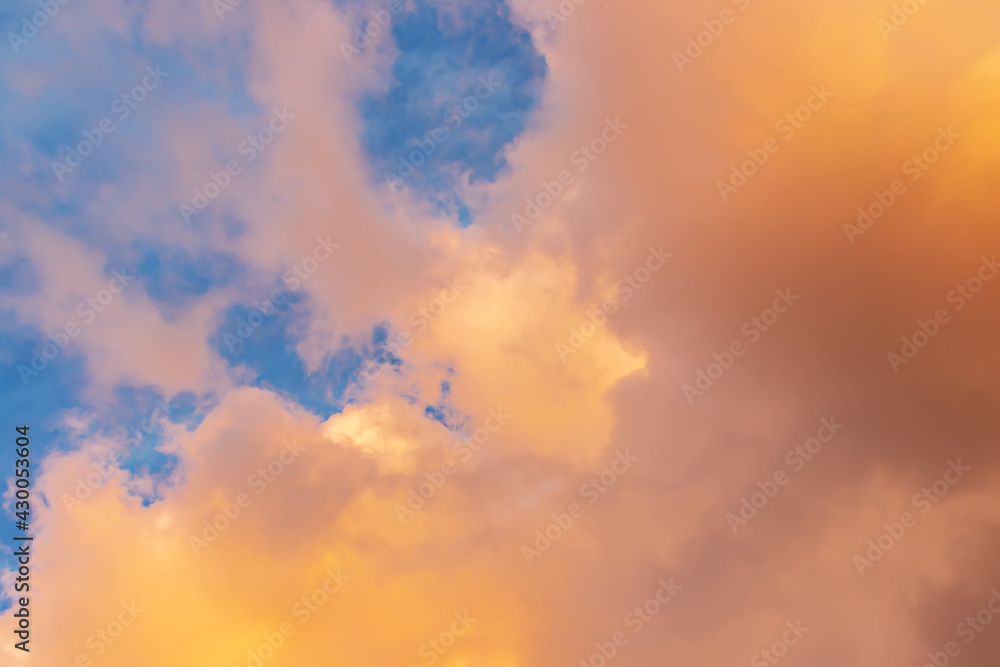 Beautiful cloudscape - pink-orange clouds in the rays of the sun against the blue sky