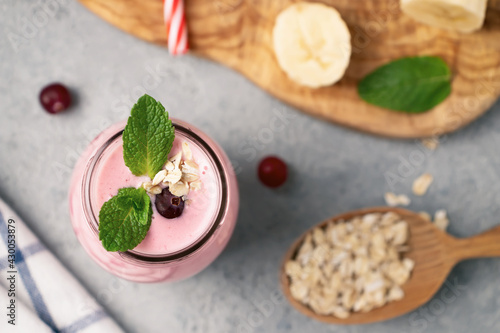 Fototapeta Naklejka Na Ścianę i Meble -  Homemade yogurt smoothie with banana, cranberry and oatmeal, top view, flat lay