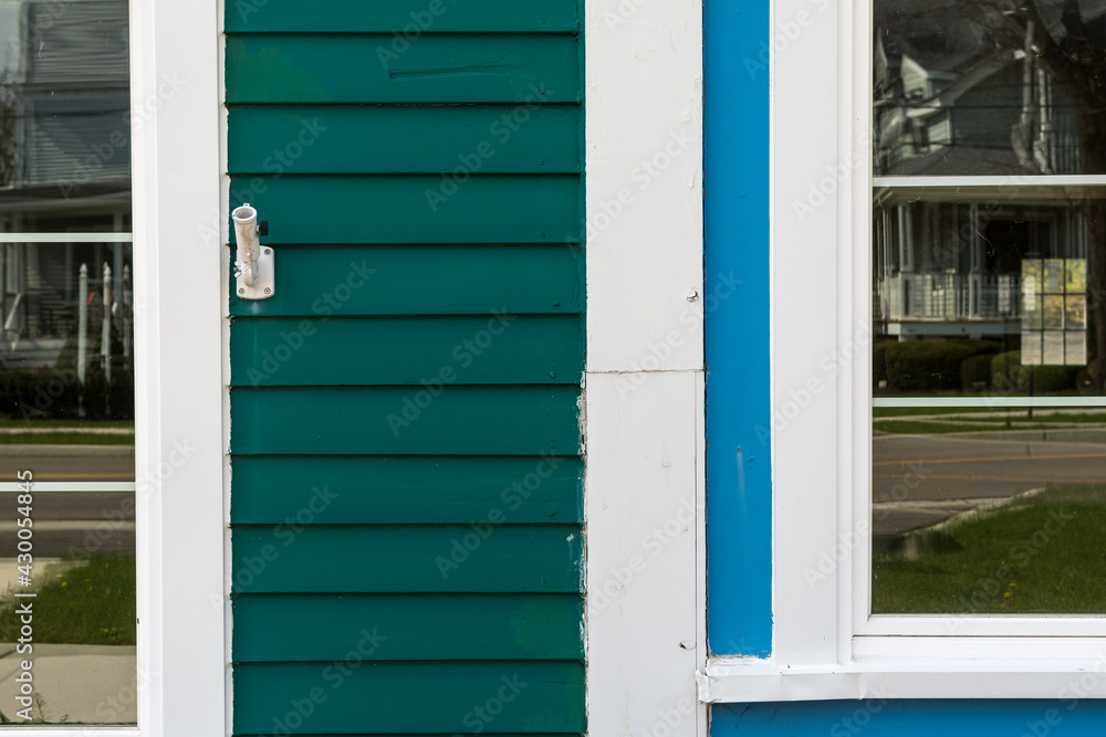 Fototapeta premium Old wooden storefronts side by side one green and one blue both with white trim; reflections in the windows of a small town