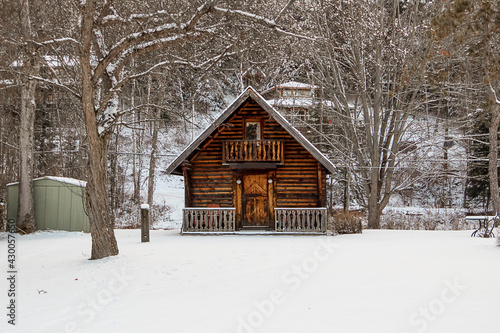 Miniature snow-covered log cabin. A cute and creative garden shed.