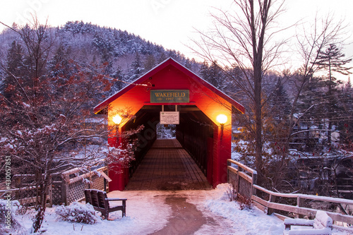 Red Covered Bridge in winter with snow-covered trees on the hillside