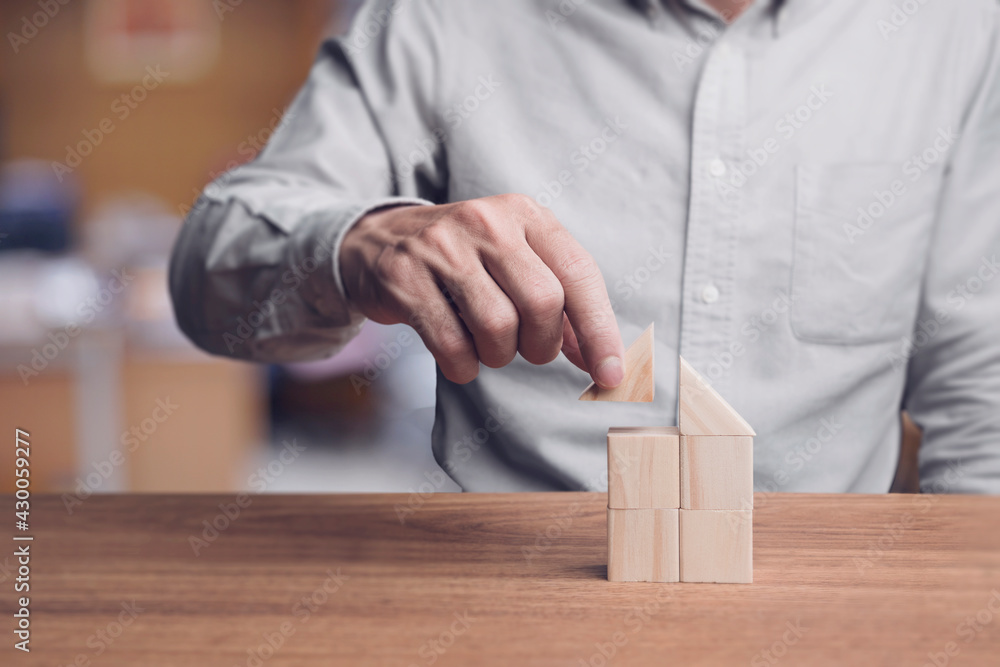 Businessman putting triangle wood on wood cube block, Building home concept. Businessman putting triangle wood on wood cube block, Building home concept.