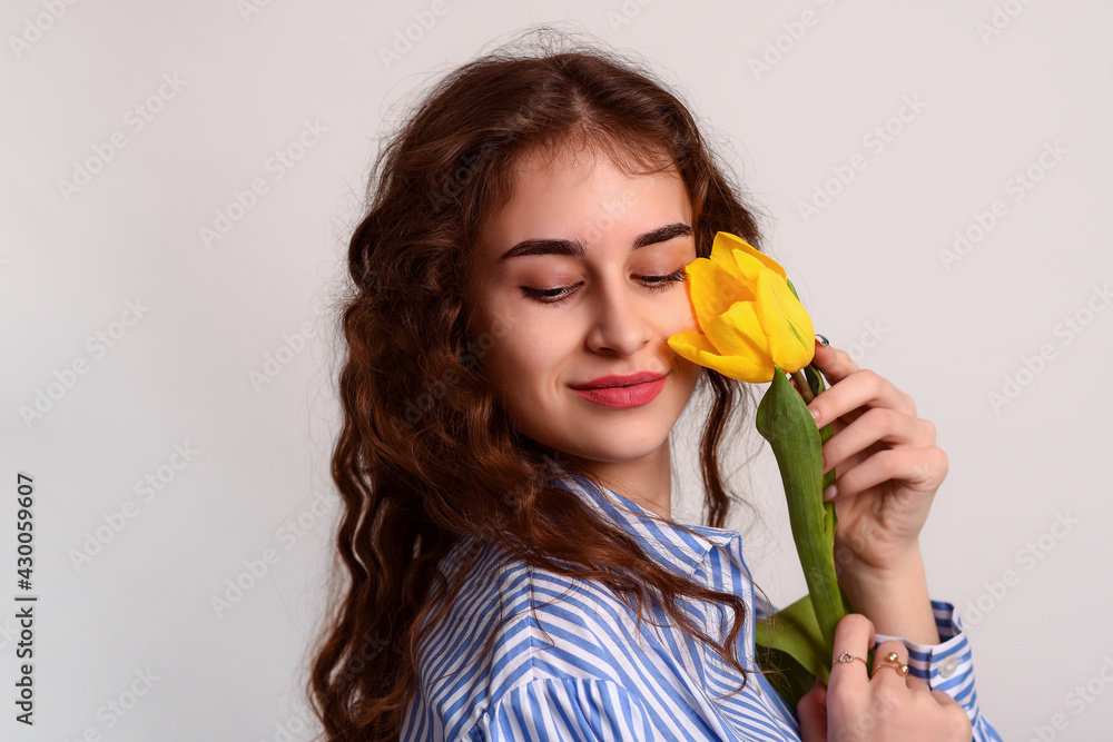 Portrait of a young woman with yellow a tulip flower close-up on a white background. Portrait of a young woman with yellow a tulip flower close-up on a white background.