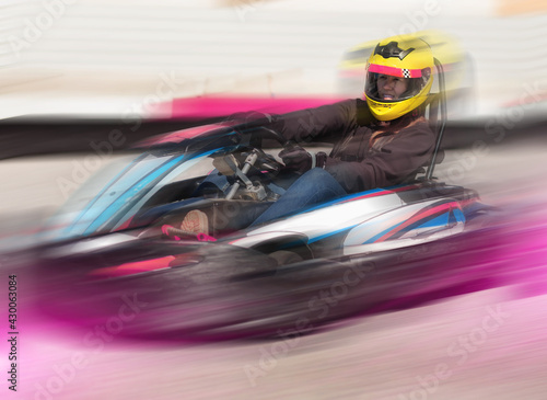 Young female in helmet driving go-kart car in sport club outdoor