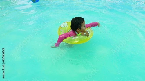 relaxing in the swiming pool in a summer hot day. refershing in holiday, a happy healthy girl playing in the pool in blue water park.  playful kid in dounut ring jumping in the water photo