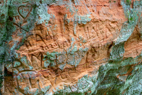 Old sandstone with handwritten lettering. Details of beige - yellow stone. Natural background. Close-up texture of sand wall.
