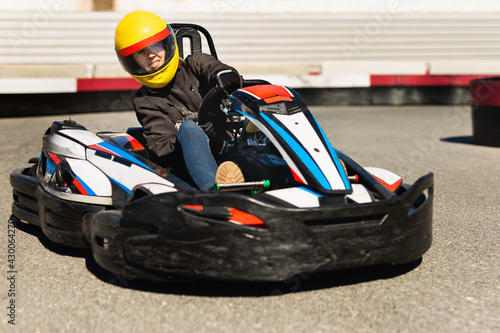 Portrait of girl in helmet driving kart at the racing track outdoors