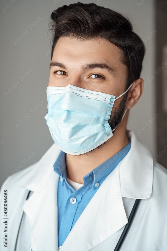 Portrait of caucasian young doctor with friendly smiling face in protective mask Portrait of caucasian young doctor with friendly smiling face in protective mask