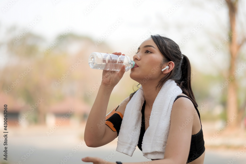 Beautiful fitness athlete woman drinking water after work out exercising on sunrise morning summer in park Beautiful fitness athlete woman drinking water after work out exercising on sunrise morning summer in park