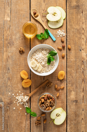 Ingredients for cooking healthy breakfast with oatmeal, dried and fresh fruits, honey and nuts on a wooden table top view. Breakfast table concept