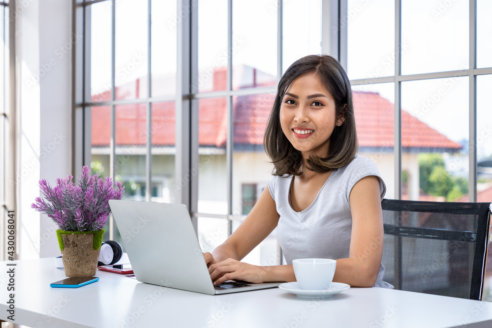 Portrait of Asian woman freelancer working at home, sitting at desk table in living room, looking at camera Portrait of Asian woman freelancer working at home, sitting at desk table in living room, looking at camera