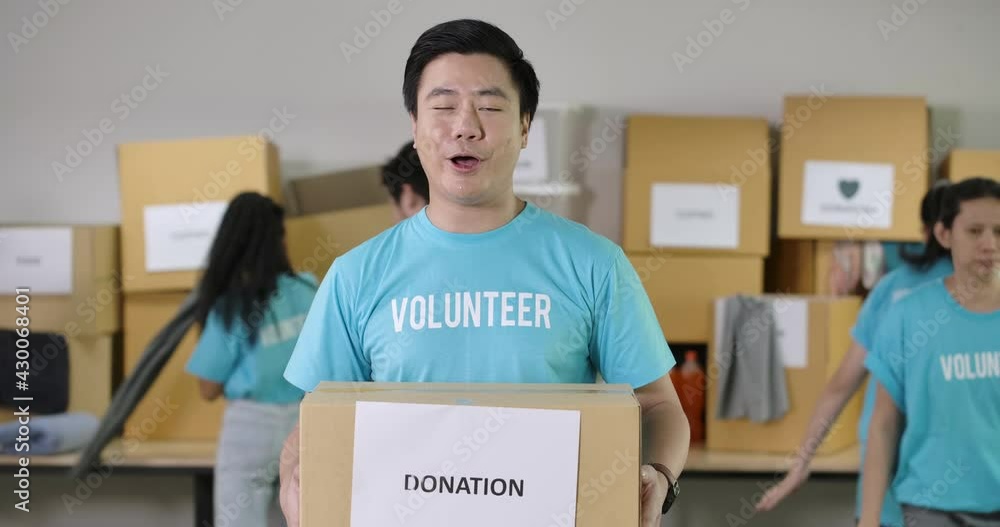 Confident young asian male volunteers looking at camera talking about the charity work and invite people to join with his community or donate things to the poor during the Coronavirus pandemic. Confident young asian male volunteers looking at camera talking about the charity work and invite people to join with his community or donate things to the poor during the Coronavirus pandemic.