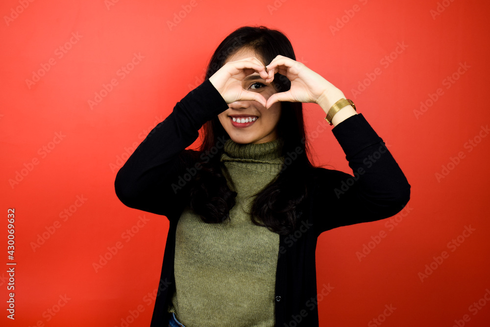 Portrait of Young beautiful asian women using black sweater make hand hearth shape with red isolated background Portrait of Young beautiful asian women using black sweater make hand hearth shape with red isolated background