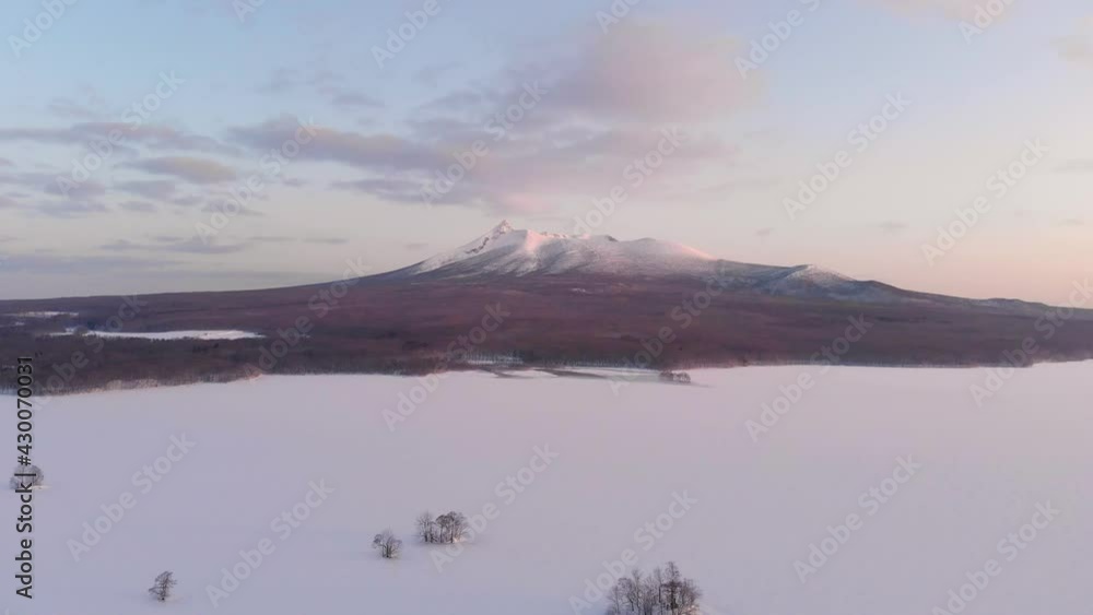 Slow aerial pull back over beautiful snow capped mountain and snowy landscape at sunrise Slow aerial pull back over beautiful snow capped mountain and snowy landscape at sunrise