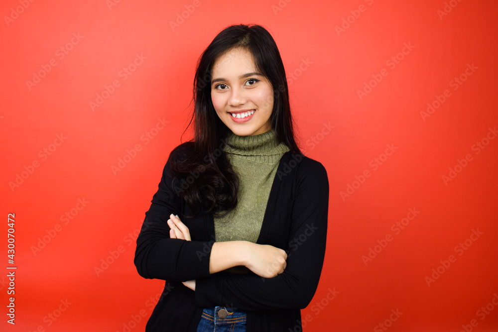 Portrait of Young beautiful asian women using black sweater crossed arms and smile with red isolated background Portrait of Young beautiful asian women using black sweater crossed arms and smile with red isolated background