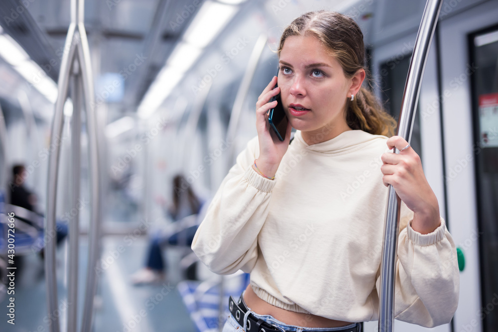Young european woman traveling by the train, using smartphone in a subway