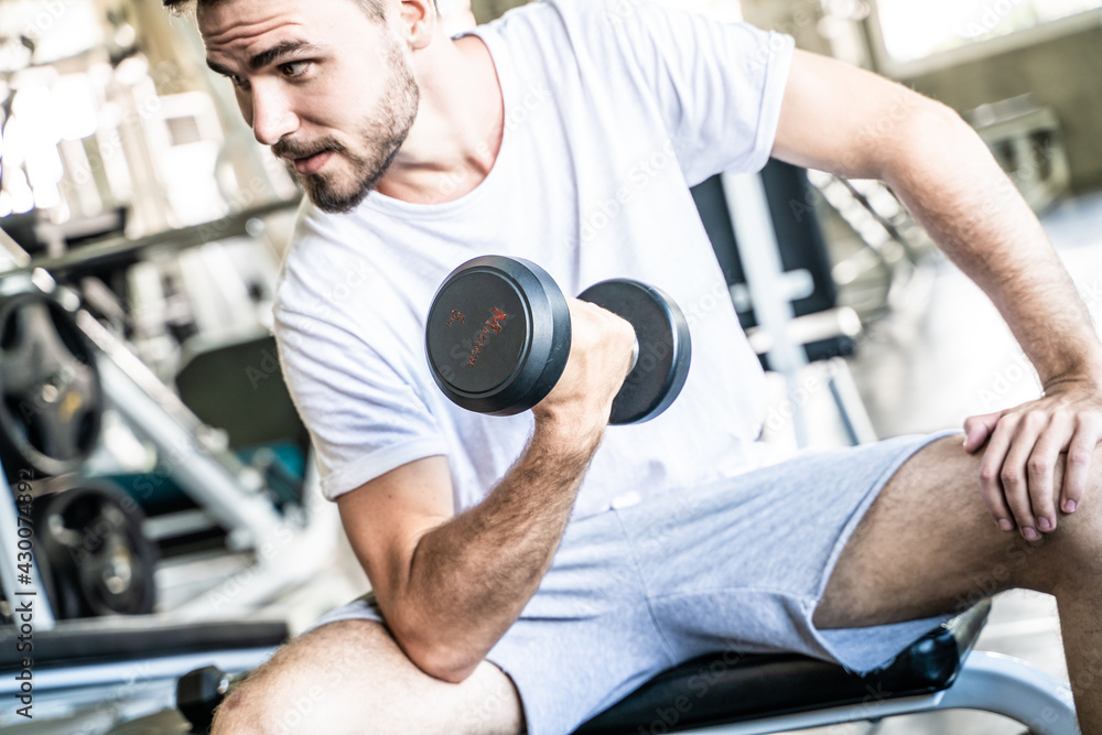 Sport man lifting up dumbbell sitting in private sport gym Sport man lifting up dumbbell sitting in private sport gym