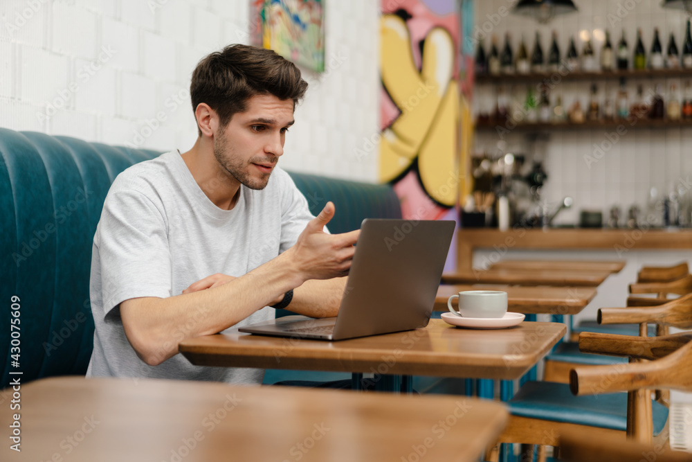 Smiling young man student sitting in cafe indoors Smiling young man student sitting in cafe indoors
