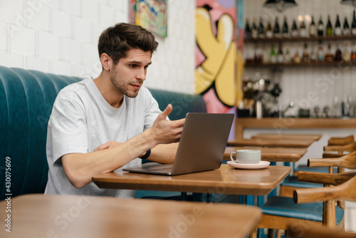 Smiling young man student sitting in cafe indoors