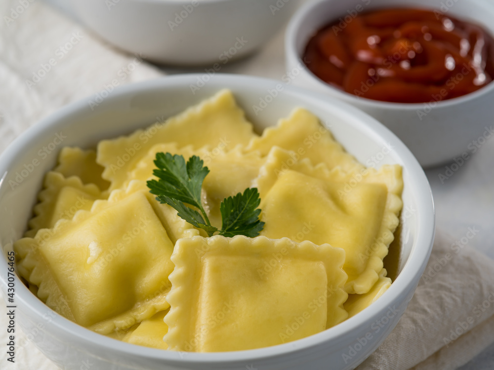 Russian dumplings or Italian ravioli with ketchup and sour cream on a light background. With cheese and mushrooms. Delicious food