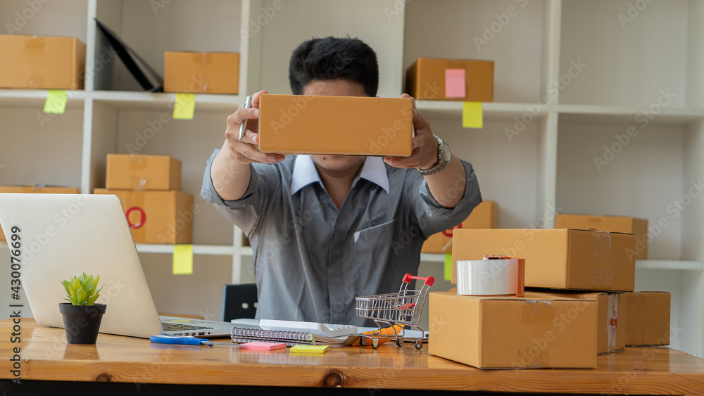Small business owners who are just starting out, working with laptops and calculators with cardboard boxes at work, small business entrepreneurs, SME working with boxes at home, selling online, e-comm Small business owners who are just starting out, working with laptops and calculators with cardboard boxes at work, small business entrepreneurs, SME working with boxes at home, selling online, e-comm