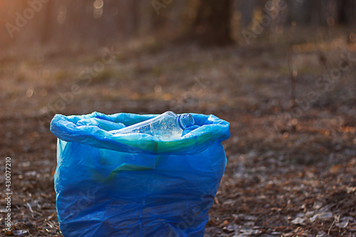 Blue bag full of garbage bottles collected in the forest in the park. The problem of environmental pollution from plastic waste.. Ecological pollution. Problem of ecology.