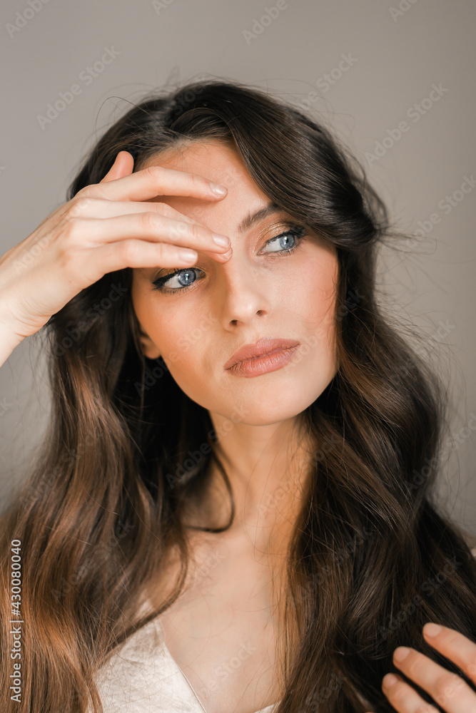 Portrait of a young brunette woman, model, looking away, picks up hair. Portrait of a young brunette woman, model, looking away, picks up hair.