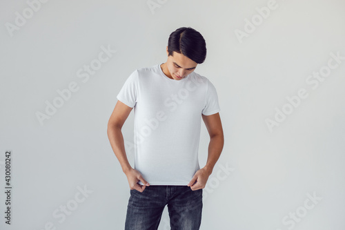 Attractive asian man in white t-shirt stands on white background. photo